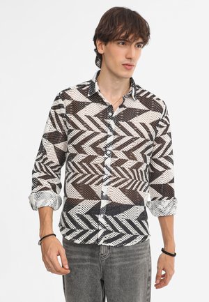 Košeľa s button-up uzáverom v čiernej, bielej a hnedej farbe. Má geometrický vzor v tvare zigzag, dlhé rukávy a kontrastný golier.