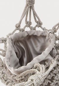 Ασημένια τσάντα με χάντρες και εσωτερική επένδυση από σατέν, με δέσιμο στη λαβή και ανοιχτό επάνω μέρος. Λεπτομέρειες από πολύπλοκες χάντρες δημιουργούν υφή στην εμφάνιση.