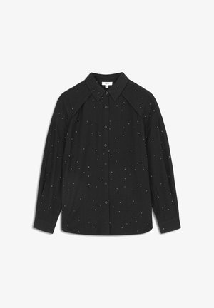Schwarzes Hemd mit Knöpfen und strukturiertem Kragen, gerippter Oberfläche und verstreuten weißen Punkten. Hat lange Ärmel und Raglan-Design.