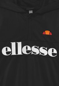 Černá mikina s kapucí s polovinio zipem. Zobrazuje logo "ellesse" v bílé barvě a barevný sluneční emblém v oranžové a červené.