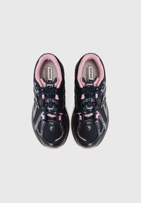 Chaussures de sport noires avec des accents roses, tige en mesh, lacets ronds et semelle intérieure rembourrée. Présente des étiquettes "New Balance" et du modèle "1906".
