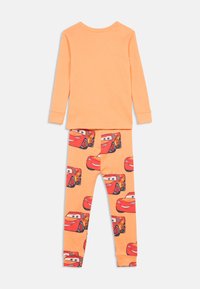 Long-sleeve orange top paired with orange pants featuring repeating red cartoon race car faces.