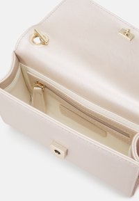 Small handbag in light beige textured material. Features gold hardware, a secure clasp, and an interior pocket with a smooth lining.