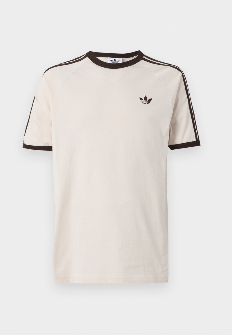 Beiges Adidas T-Shirt mit schwarzem Kragen, Ärmelsäumen und drei schwarzen Streifen entlang der Schultern; Adidas-Logo auf der linken Brust.