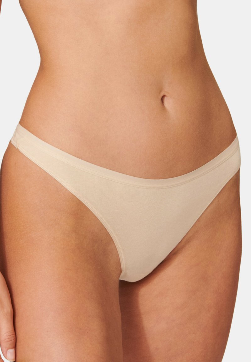 Beige stringtruse med en glat overflade, tynd elastisk taljeelastik og sømløse kanter, designet til minimal dækning og komfort.