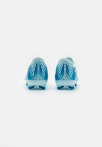Botas de fútbol en un degradado azul claro, con un diseño texturizado y tacos azules. La parte trasera cuenta con un detalle de marca y un patrón de rayas.