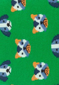 Grüner Strickstoff mit einem wiederholten Muster von stilisierten Tiergesichtern mit orangen Akzenten, blauen und weißen Details sowie schwarzen Merkmalen.