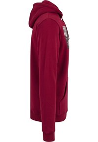 Sudadera roja con capucha y bolsillo delantero, confeccionada en tela suave. Cuenta con capucha con cordón y un diseño estampado en el pecho. Textura lisa y mangas ajustadas.