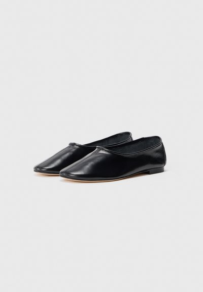 Ballerine in pelle nera con punta affusolata e tacco basso, caratterizzate da una consistenza liscia e un design semplice senza hardware o dettagli aggiuntivi.