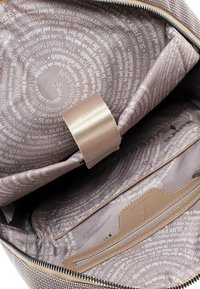 Wnętrze torby z jasnobrązowej tkaniny z okrągłym wzorem tekstowym. Zawiera gładką kieszeń na zamek oraz widoczny, beżowy pasek.