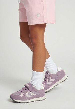 Benendelen met lichtroze korte broek, witte geribbelde kniekousen en paarse sneakers met witte Chevron-strepen en klittenbandsluitingen.