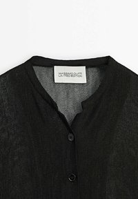 Cardigan léger en maille noire avec un col rond, deux boutons et une étiquette blanche indiquant "Massimo Dutti Limited Edition."