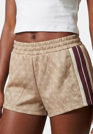 Pantalones cortos beige estampados con cintura elástica, con franjas laterales en granate y blanco y el logo "GUESS", combinados con un top corto blanco.