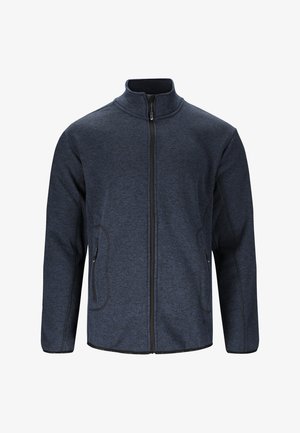 Tummansininen vetoketjullinen takki, jossa korkea kaulus, teksturoidusta kankaasta, kaksi sivutaskua ja kontrastivärinen musta reunus vetoketjun ja saumojen varrella.