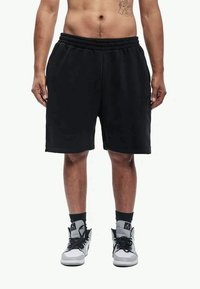 Pantaloni scurți atletici negri cu talie elastică, buzunare laterale și croială lejeră, asortați cu adidași înalți gri și negri.