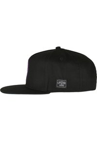 Sort snapback-cap med flad skygge, der har et broderet logo foran og et mærke på siden. Glat stofstruktur.