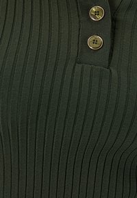 Haut en tricot côtelé vert foncé avec deux boutons ronds près de l'encolure, fini texturé et motif à rayures verticales.