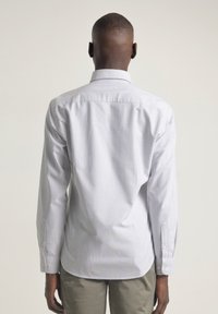 Camisa de manga larga a rayas en azul claro y blanco, con cuello abotonado, corte regular, con una textura suave y detalles de botones en los puños.