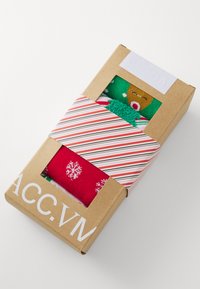 Boxset mit bunten Socken; eine grüne Socke mit Lebkuchenmotiv, eine rote Socke mit Schneeflockenmustern. Illustriert verpackt mit gestreiften Akzenten.