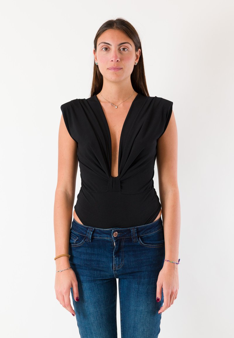 Body nero con scollo a V profondo e dettagli in tessuto drappeggiato, abbinato a jeans blu aderenti. Materiale liscio ed elastico con maniche corte a cappuccio.