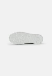 Suola di sneaker bianca con superficie in gomma texture, caratterizzata da un motivo a spina di pesce e punti di trazione circolari per una migliore aderenza. Design della punta rotonda.