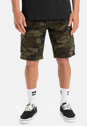 Camo cargo shorts in dark green and brown fabric, featuring side pockets. Worn with white socks and black shoes with white accents.