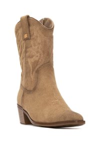 Botas de cowboy de ante en tono marrón claro con un tacón bajo, caña curva y costuras decorativas. Incluyen una pestaña para facilitar el calzado.