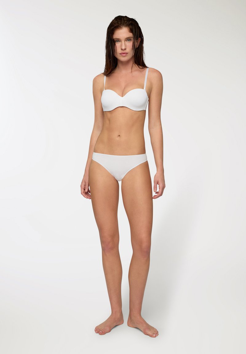 Reggiseno bianco imbottito con spalline regolabili, abbinato a slip hipster bianchi semplici, con una texture del tessuto liscia e un design minimalista.