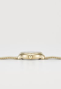 Gold-tone watch with a round case, white dial, and a textured gold mesh strap. Features a single crown on the side.