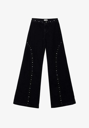 Vaqueros negros de pierna ancha con detalles de tachuelas plateadas a lo largo de las costuras de las piernas y la cintura, con cierre frontal de botón y cremallera.