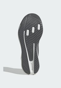 Suela de goma negra con un patrón texturizado, que cuenta con acentos en blanco y tres recortes circulares. El diseño incluye un detalle de logo y un borde suave.