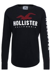 Men's long-sleeve black T-shirt made of cotton. Features a red graphic bird logo and "HOLLISTER CALIFORNIA" text in white. Simple crew neck.