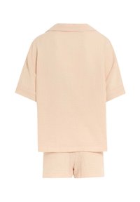 Perzikkleurige pyjama set met korte mouwen en korte broek, gemaakt van een gestructureerde stof. De simpele kraagdetail versterkt het ontspannen ontwerp.