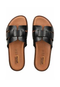 Schwarze Leder-Sandalen mit breiten Riemen, die ein zentrales geometrisches Akzentstück aufweisen. Texturierte braune Innensohle mit Markenlogo, flache Sohlenform.