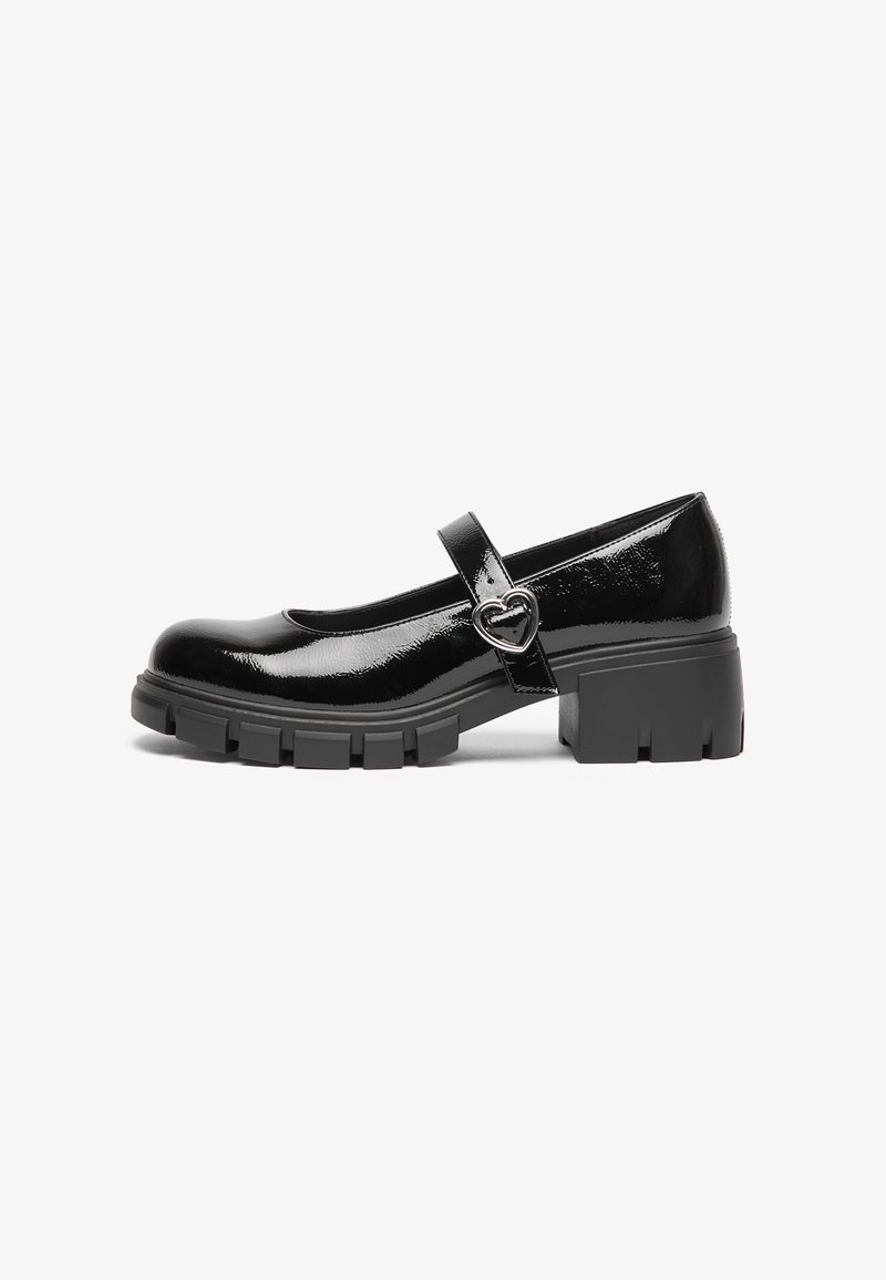 Chaussures Mary Jane en cuir verni noir présentant un bout arrondi plat, une bride avec une boucle en forme de cœur, et une semelle épaisse texturée.