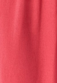 Strikket stof i en lys koralfarve, med en fin struktur og subtile variationer, jævn overflade og ingen synlige mønstre eller accenter.