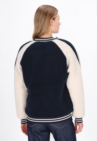 Marineblå og creme fleecejakke med raglanærmer, stribede manchetter og kant, tekstureret stof og en afslappet pasform.