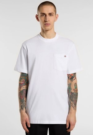 Maglietta bianca in cotone con scollo tondo, maniche corte e tasca sul petto con logo. Texture liscia con vestibilità classica.