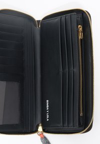 Billetera de cuero negro con cierre de oro, múltiples ranuras para tarjetas, un bolsillo transparente para identificación y una etiqueta de marca "BIMBA Y LOLA" en el interior.