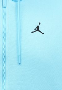 Ανοιχτό μπλε ζακέτα με φερμουάρ από υφαντό ύφασμα. Περιέχει ένα μαύρο κεντημένο λογότυπο Jumpman στο στήθος και ταιριαστά εξαρτήματα φερμουάρ.