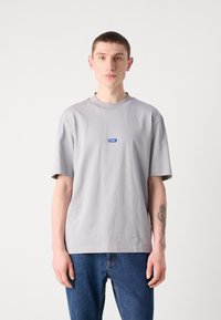 Hellgraues Baumwoll-T-Shirt mit Rundhalsausschnitt, kurzen Ärmeln und einem blauen Etikett mit dem Markennamen auf der Brust.
