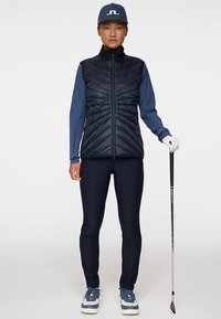 Laivastonsininen tikattu liivi sinisen pitkähihainen paidan päällä, yhdistettynä laivastonsinisiin housuihin ja sinisiin tennareihin. Pitää golfmailaa kädessään ja käyttää sinistä lippalakki.