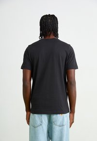 Sort kortærmet t-shirt set bagfra, lavet af bomuld med en glat tekstur. Skjorten har en rund halsudskæring og en lige pasform.