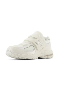 White athletic shoe with a synthetic upper, mesh accents, circular logo, and a hook-and-loop strap. Features a textured rubber sole.