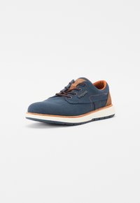 Zapatilla navy azul con un upper de malla texturizada, acentos de cuero marrón, cierre con cordones y una suela blanca contrastante.
