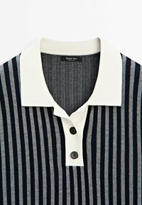 Striped polo shirt in navy, gray, and cream. Features a cream collar, two black buttons, and a textured fabric with vertical stripes.