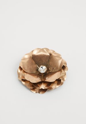 Metallene Blumenbrosche aus gebürstetem Bronze, mit abgerundeten Blütenblättern und einem zentralen klaren Edelstein. Strukturierte Oberfläche mit geschichtetem Design.