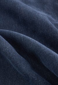 Tamsiai mėlynas audinys su lygiu, tekstūruotu paviršiumi, pasižymintis subtiliais atspalvių skirtumais ir minkštu, pintu išvaizda.