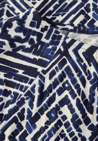 Tejido de algodón con un patrón geométrico en azul oscuro y blanco, con formas abstractas y audaces y diferentes texturas de línea en todo el diseño.