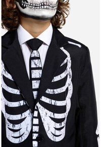 Black suit featuring a skeletal design in white, with a matching tie. The suit has a textured fabric and printed ribcage detail on the torso.